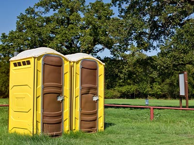 two yellow portable toilets at a park